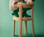 Person seated on a Bla Station Frankfurter chair in natural timber finish, shown in a studio setting.