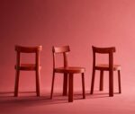 Bla Station Frankfurter red timber chairs with a natural timber table in a studio setting.
