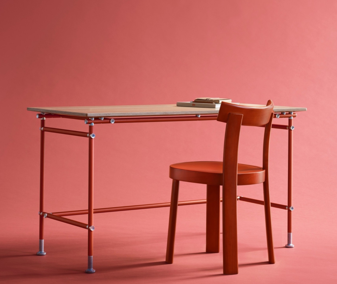 Bla Station Frankfurter chair in red timber paired with the Able Table in a studio setting.