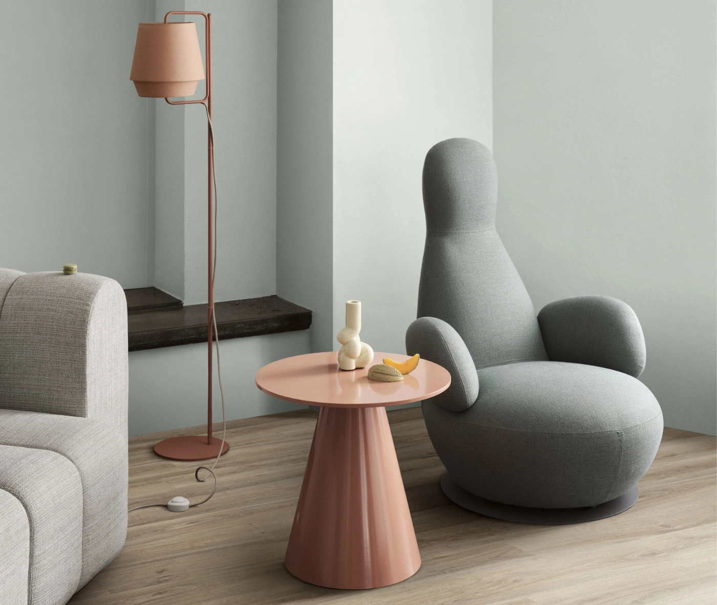 Bla Station Jackless table and Oppo lounge chair in a lounge setting with grey upholstery and a sculptural form.