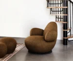 Bla Station Oppo lounge chair in a lounge setting with fully upholstered brown fabric and a rounded sculptural design.