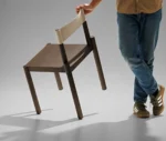 True Adinne hospitality chair in a studio setting with leather backrest and dark timber frame.