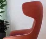 Close-up in side view of True Ahkka lounge chair with curved upholstered shell and headrest.