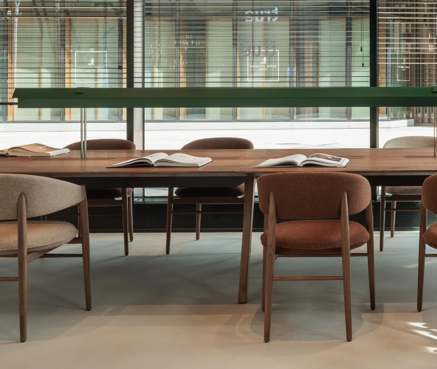 True Aura chair surrounding Wing table, with an upholstered seat and backrest with solid timber legs.