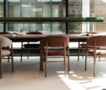 True Aura chair surrounding Wing table, featuring an upholstered seat and backrest with solid timber legs in a showroom setting.
