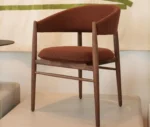 True Aura lounge chair in showroom setting shown in front-left view, with upholstered seat and timber legs.