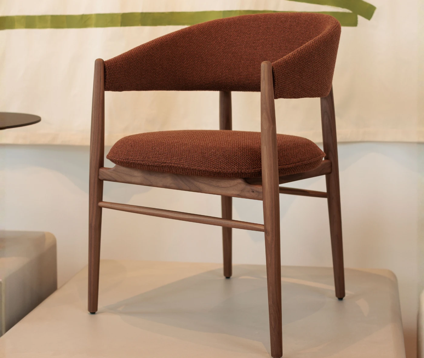 True Aura lounge chair in showroom setting shown in front-left view, with upholstered seat and timber legs.