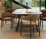 True Aura chair surrounding Wing table in a showroom setting, with upholstered seats and timber legs.