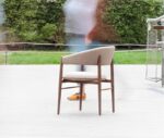 True Aura lounge chair in outdoor setting with wraparound backrest and upholstered seat.