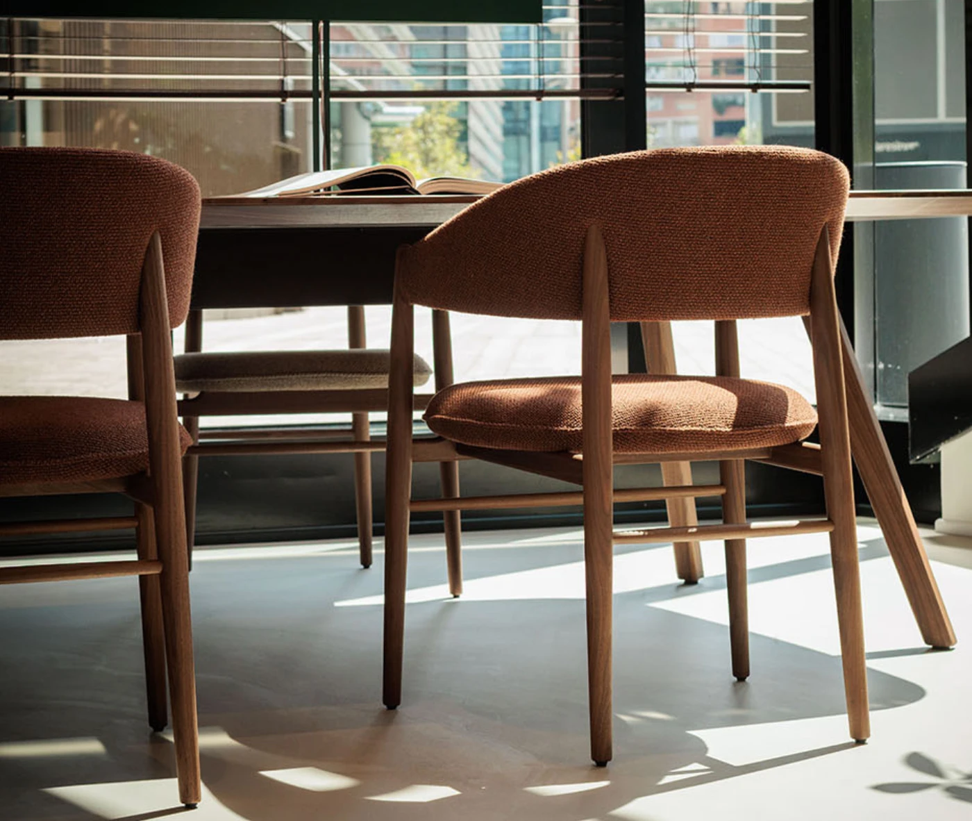 True Aura chairs in meeting setting with wraparound upholstered backrests and timber frames.