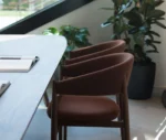 True Aura chairs in meeting setting, in side view with upholstered backrests and timber frames.