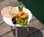 True Cloud round table with a white finish and removable timber tray in an outdoor setting.