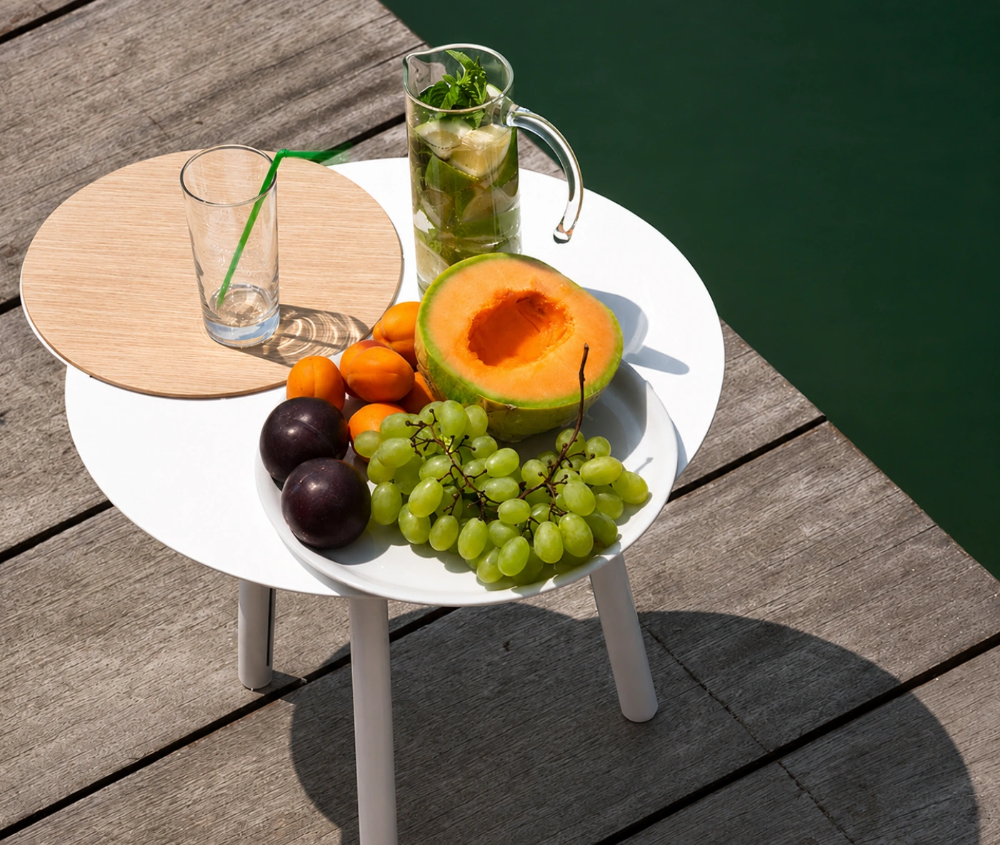 True Cloud round table with a white finish and removable timber tray in an outdoor setting.