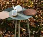 True Cloud round table with light and dark green finish and removable timber tray in an outdoor setting.