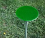 True Cremino table in outdoor setting with layered round glass tabletop in green finish.