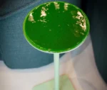 Detail of True Cremino table in showroom setting with layered round glass tabletop in green finish.