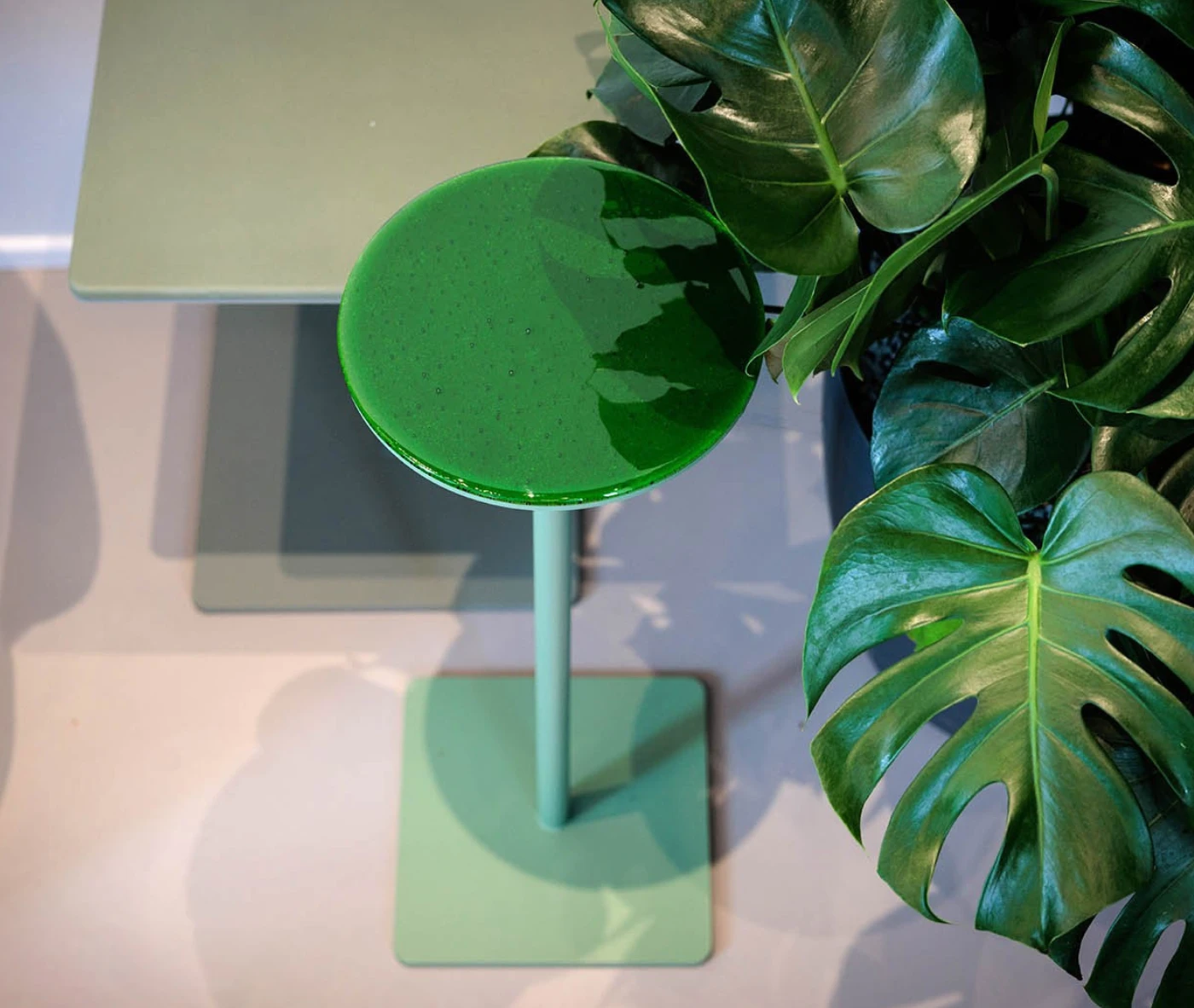 True Cremino table in showroom setting with layered round glass tabletop in green finish.