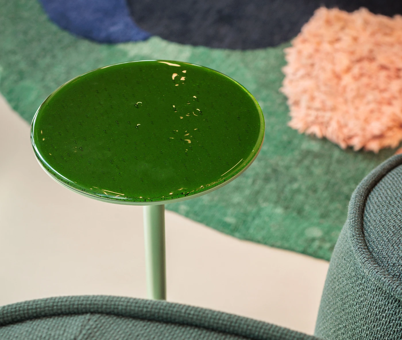 Close-up of the True Cremino table in a showroom setting, with a green glass tabletop.