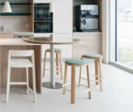 True Cute stools with green upholstered seat, timber legs, circular footrest in a kitchen setting.