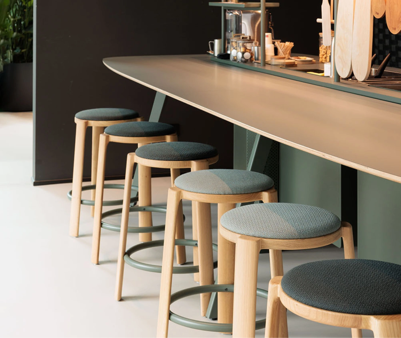 True Cute stools with dark upholstered seats, timber legs, circular footrests in a hospitality setting.