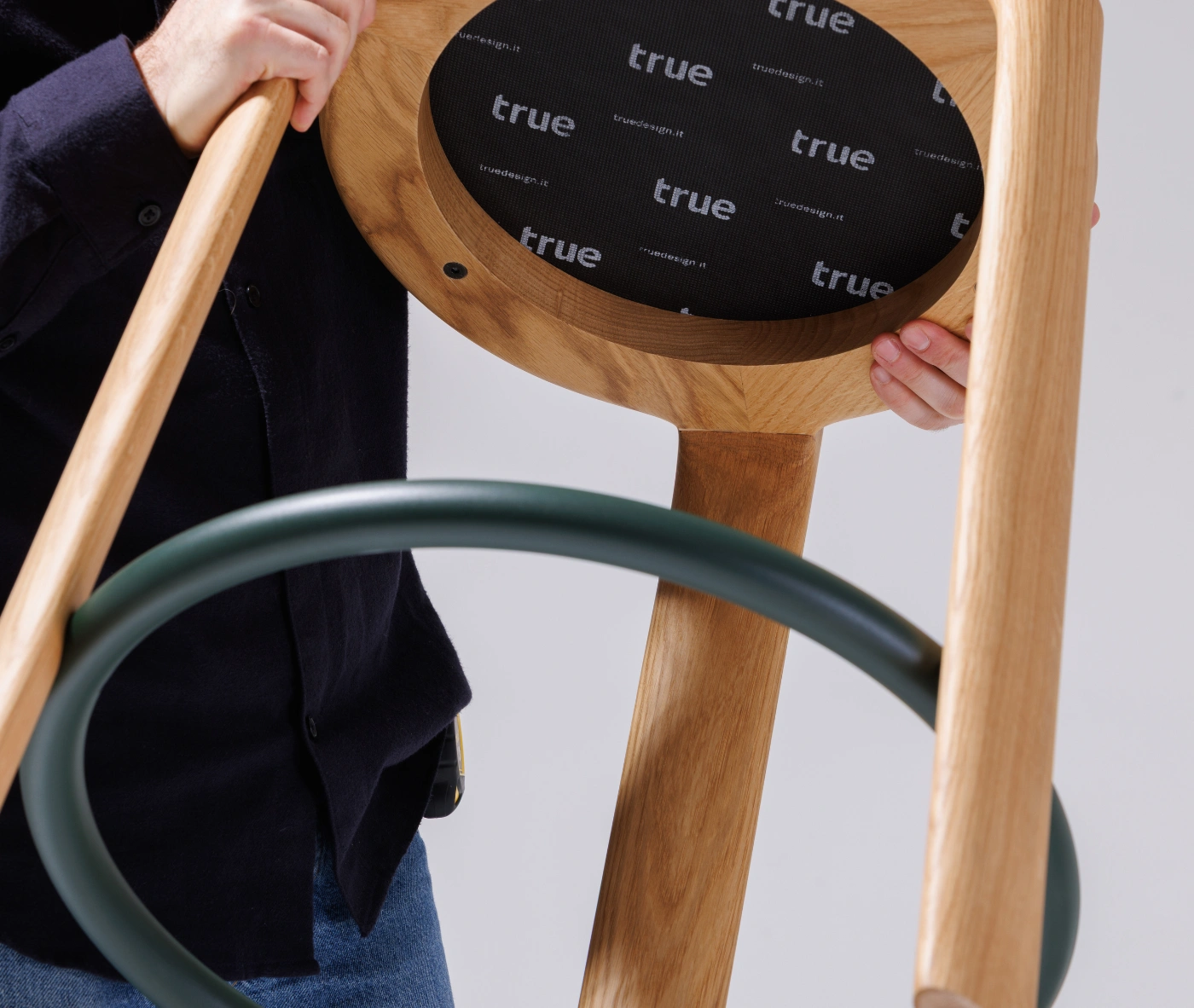 Close-up of the True Cute stool, highlighting its upholstered circular footrest and timber legs.