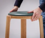 Close-up of the True Cute stool, highlighting its upholstered seat and timber frame.