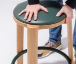 Close-up of the True Cute stool, highlighting its cushioned upholstered seat and timber frame.