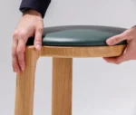 Close-up of the True Cute stool, highlighting its upholstered seat and timber frame.