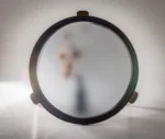 True Cute top view of round occasional table with glass top and timber legs in a studio setting.