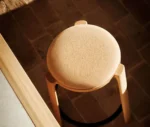 Top view of True Cute with upholstered seat, timber legs, and circular footrests in a dining setting.
