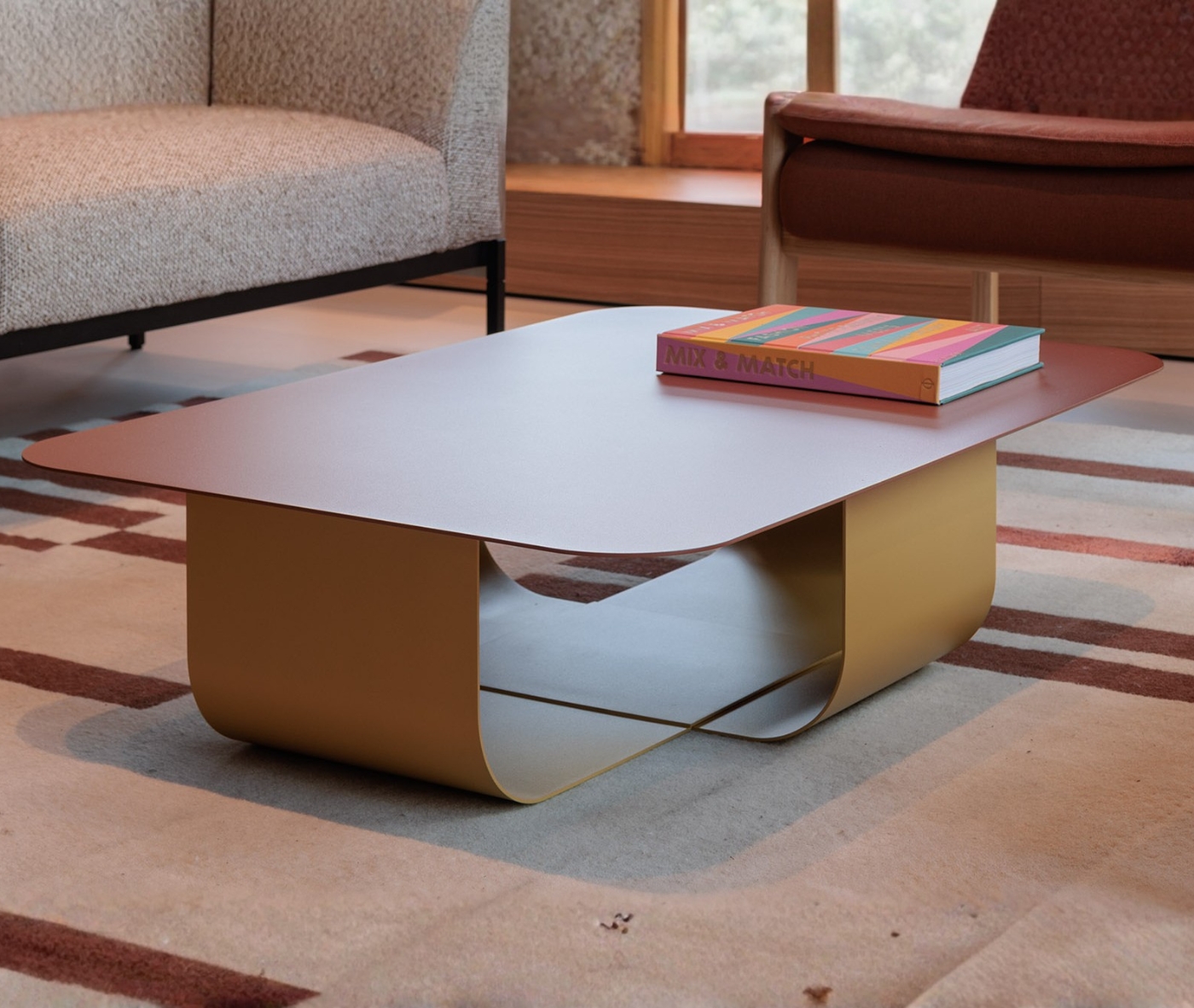 True Fiocco table in lounge setting with soft-edged rectangular top and short curved metal base.