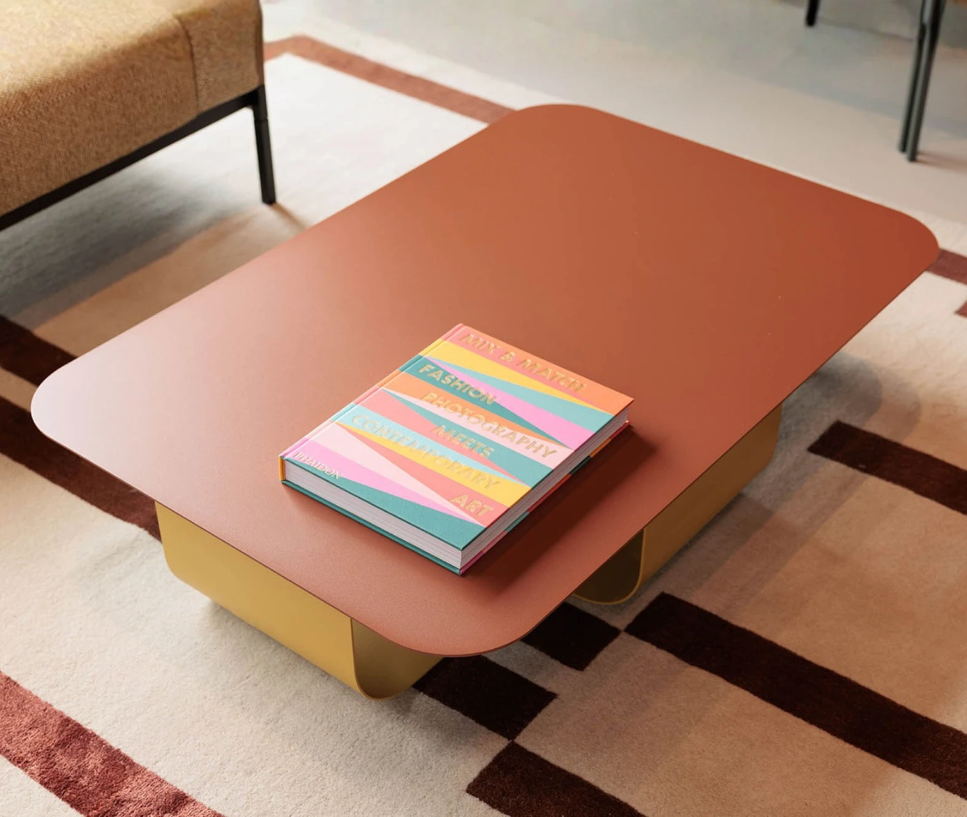 True Fiocco table in elevated view in lounge setting with soft-edged rectangular top and curved metal base.