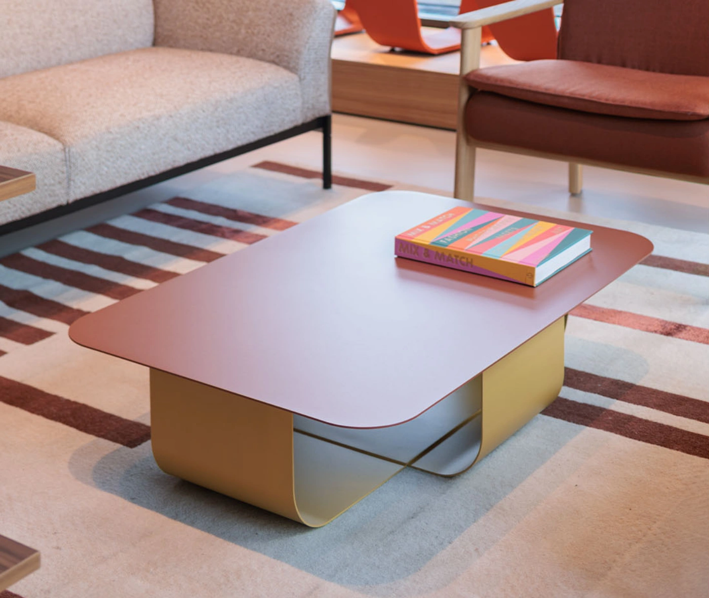 True Fiocco table in front-right view in lounge setting with soft-edged rectangular top and curved metal base.