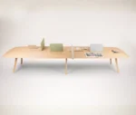 True Wing Working table in front view with light timber top and frame, padded divider screens, and workspace accessories.