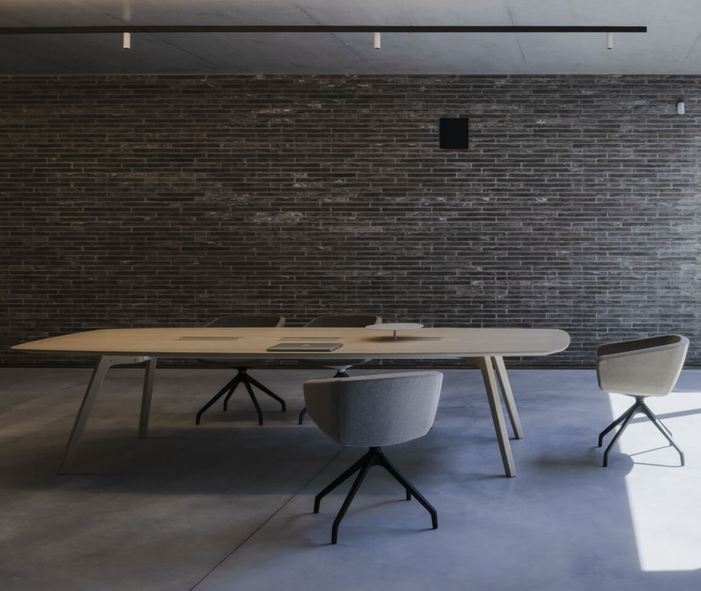 True Wing table in a meeting setting with a light timber tabletop and timber legs, surrounded by Arca chairs.