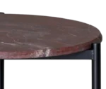 Half close-up view True Blade coffee table with a rounded red marble top and slim metal legs.