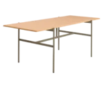 Blade table, front-left view with a long natural timber tabletop and dark metal frame.