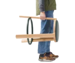 True Cute stool shown being carried by a person, highlighting its timber frame and circular footrest.