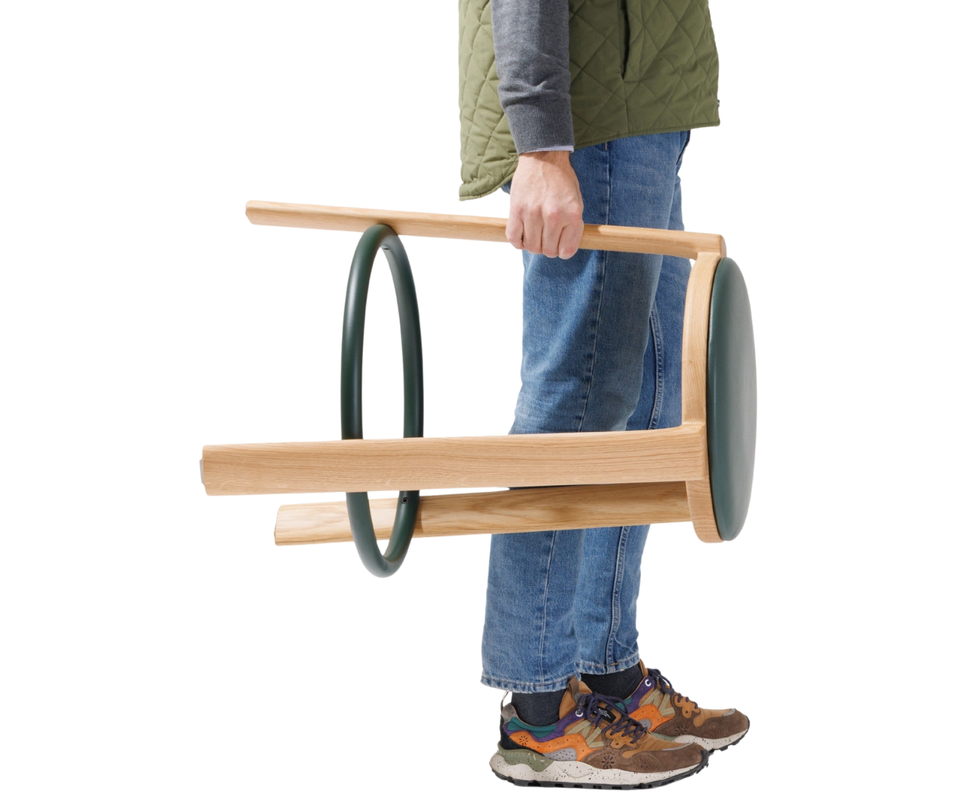 True Cute stool shown being carried by a person, highlighting its timber frame and circular footrest.