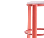 Half close-up view of True Cute stool with a light pink upholstered seat, long red timber legs and a circular footrest.